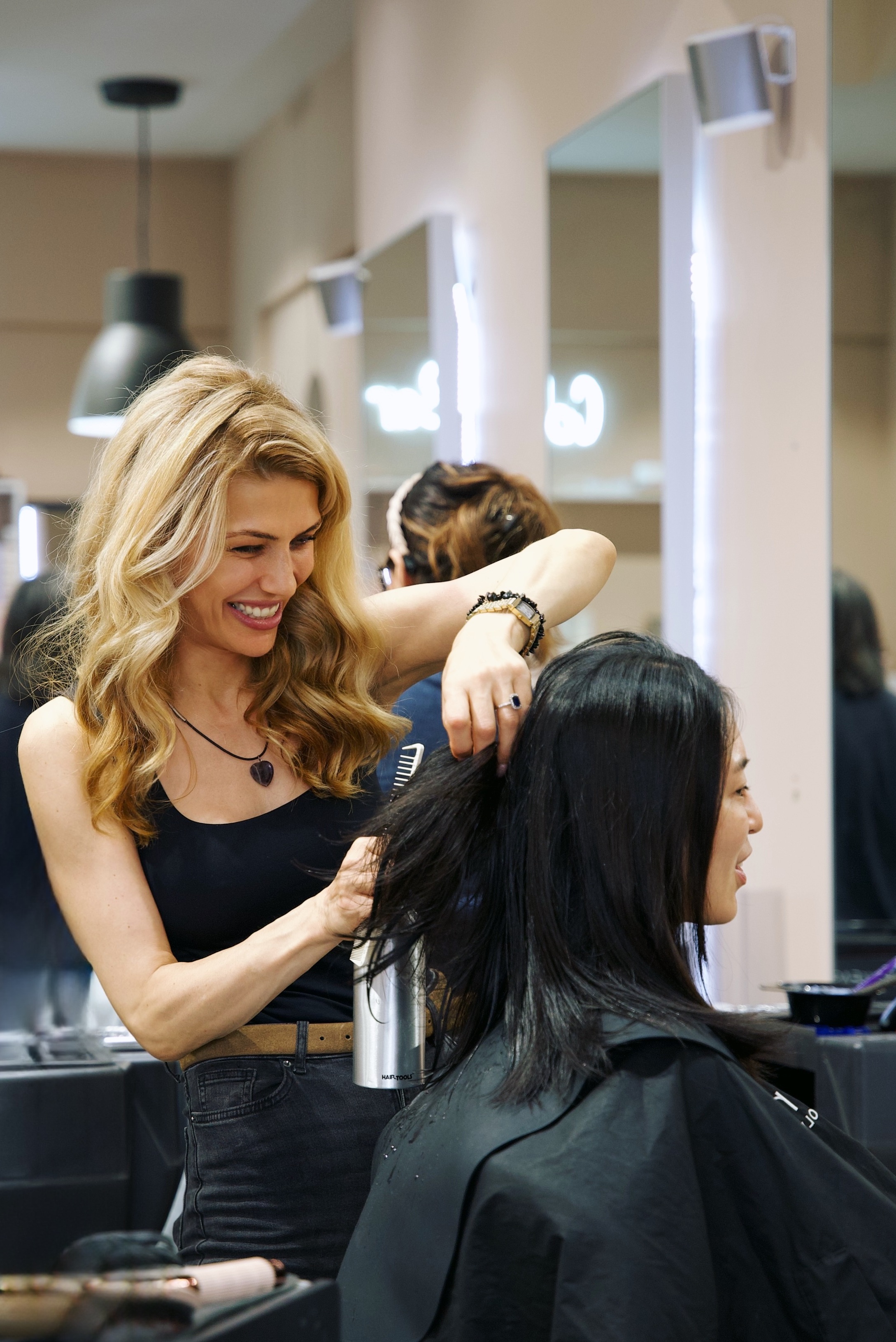 An Alo stylist blow-drying and styling a client's hair