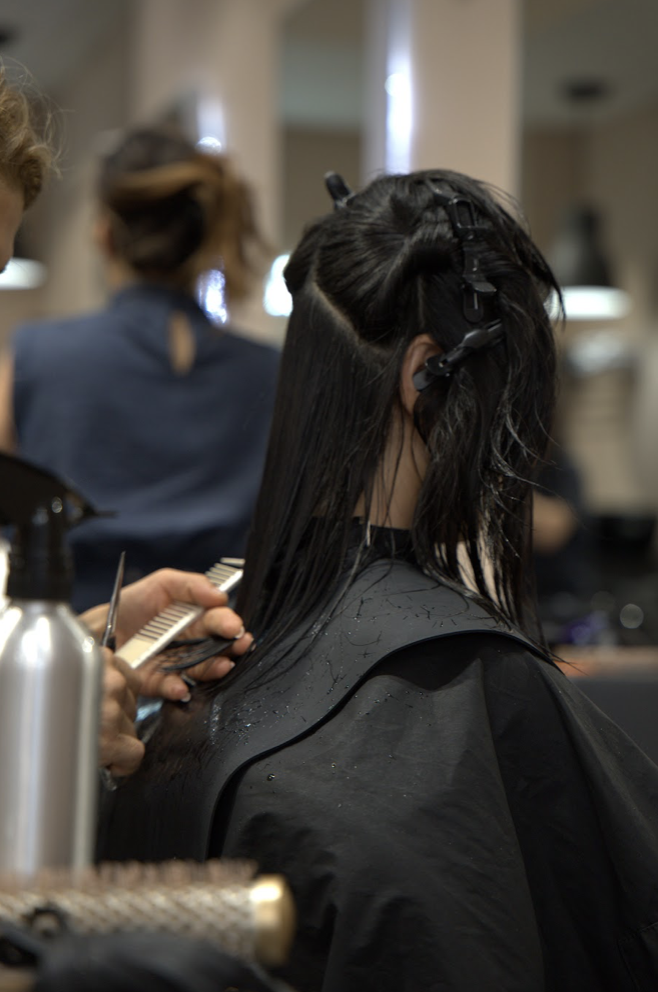 An Alo stylist sectioning and cutting a client's hair
