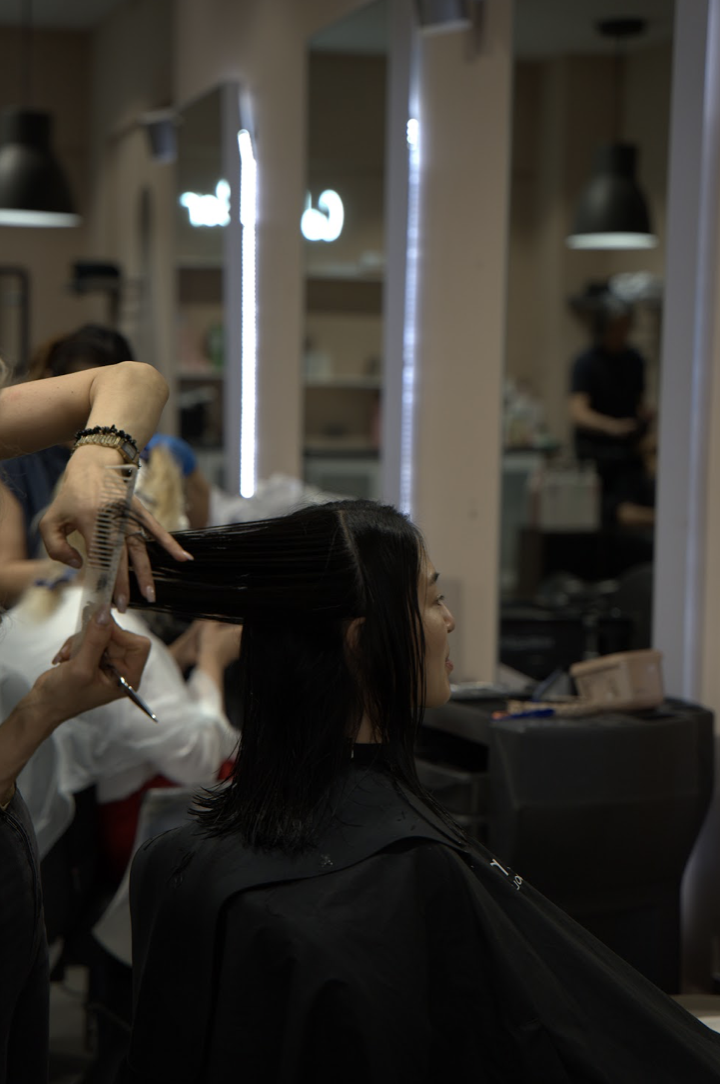 An Alo stylist combing and cutting a client's hair